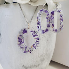 Load image into Gallery viewer, Handmade real flower oval pendant necklace accompanied by a pair of stud dangling earrings made with purple statice and silver flakes preserved in resin. Resin Flower Jewelry - Necklace And Earring Set